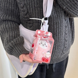 Pink plush doll in clear milk carton display case hanging on a purple handbag