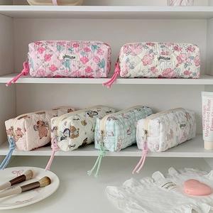 Detailed view of quilted cotton pouches featuring floral and cartoon bear patterns