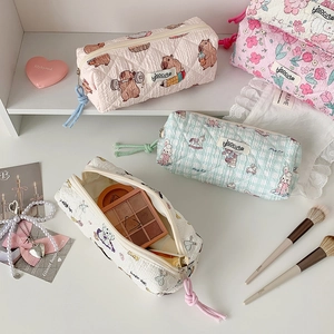 Close-up of quilted floral pencil cases and makeup bags with colorful woven zipper pulls