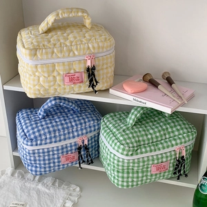 Detailed close-up of quilted checkered makeup bags with pink zippers and handle