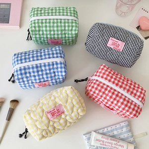 Vue à plat de trousses de maquillage à carreaux matelassées cœur avec accessoires pastel