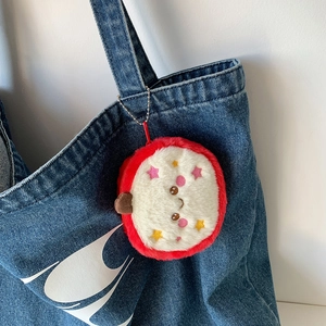 Süße Drachenfrucht-Plüschtasche als Schlüsselanhänger an einer blauen Jeans-Tasche