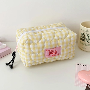 Detail of yellow checkered makeup bag with heart quilting and pink woven label