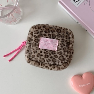 Detailed macro shot of a leopard print plush pouch with pink woven zipper pull handle