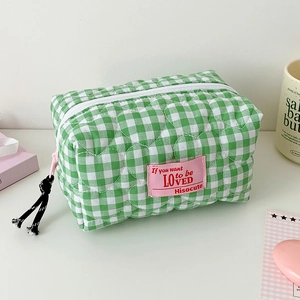 Close-up of green checkered quilted pencil case with heart embroidery and zipper