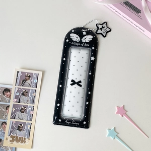 Détail du porte-carte en acrylique noir avec motifs d'ailes et pendentif en étoile