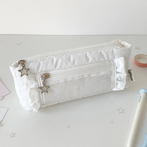 Detail of white pleated stationery bag featuring gold star zippers and ruffled edges