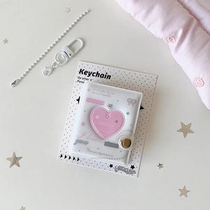 Macro shot of a pink heart-shaped mini photo album keychain with metal bead chain