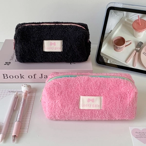 Detailed view of plush lambskin pencil cases in black and pink with contrast zippers