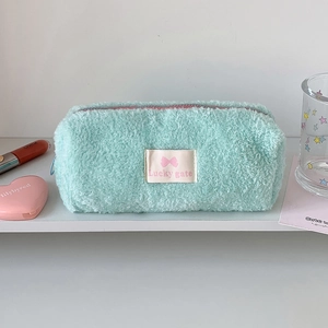 Close-up of mint green plush pencil case with Lucky gate label on a white shelf