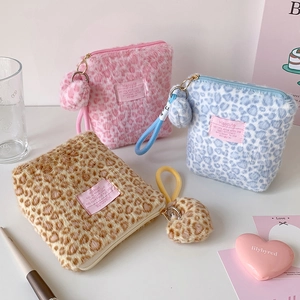 Detailed view of plush leopard print makeup bags in pink, blue, and brown with gold zippers