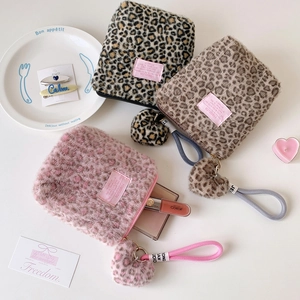 Flat lay of small leopard print plush cosmetic bags in pink and brown with heart charms