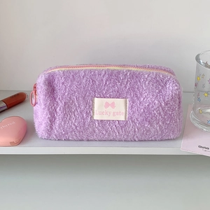 Detail of purple fluffy plush pencil case featuring Lucky gate patch and pink zipper closure
