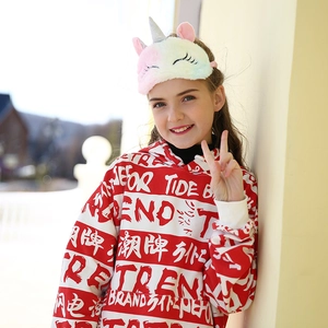 Outdoor lifestyle shot of a plush unicorn sleep mask and a red striped hoodie