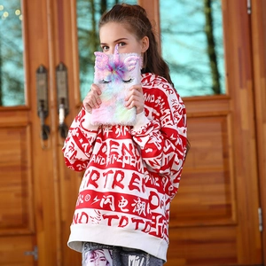 Detail of cute plush unicorn notebook held by model in street style hoodie