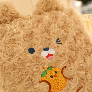 Close-up of brown teddy fleece tablet sleeve featuring cute embroidered bear and orange character