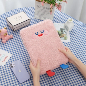 Detail of pink plush tablet sleeve with embroidered face and 3D feet on plaid fabric