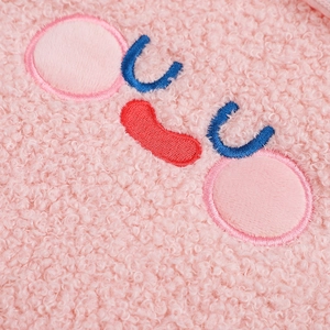 Close-up of pink sherpa fleece fabric with detailed blue and red geometric embroidery