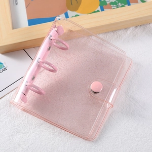 Detail of 3-hole mini PVC binder with pink metal rings and glitter finish on white surface