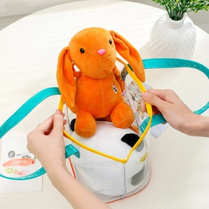 Detail view of transparent PVC bear tote bag with blue handles and orange plush toy