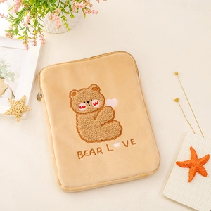 Detail of plush beige tablet sleeve featuring embroidered teddy bear and metal zipper