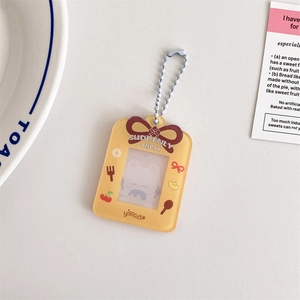 Detail of yellow acrylic card holder with cherry bow patterns and silver bead chain