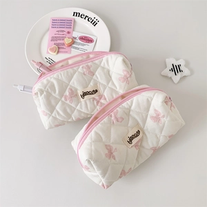 Detail of quilted white pencil case featuring pink butterfly prints and a pink zipper closure