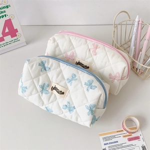 Detailed macro view of quilted cotton pencil cases with blue and pink bow patterns