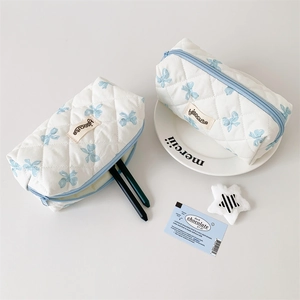 Close-up of quilted pencil case with blue bow patterns and zipper detail showing pen storage