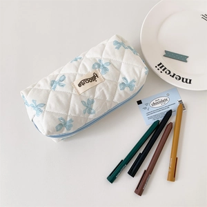 Detailed shot of cream quilted pencil case with blue bow patterns and zipper closure