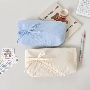 Dettaglio di astucci in tessuto azzurro e beige con decorazione di chiusura a nastro