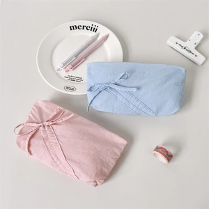 Dettaglio di pochette minimaliste in cotone con coulisse rosa e blu per cancelleria