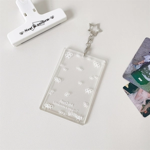 Detail of transparent acrylic card holder with bow print and star-shaped silver hook