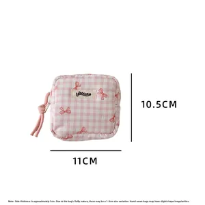 Detail view of small pink checkered cosmetic bag with bow print and 11x10.5x5cm dimensions
