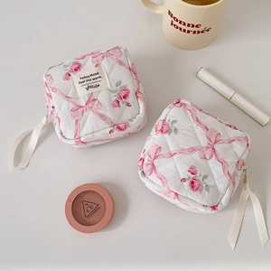 Detailopname van de gewatteerde make-uptas met roze bloemen en strikpatronen
