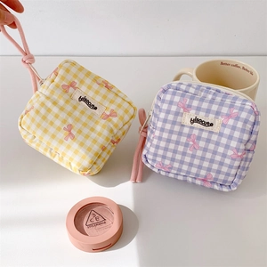 Close-up of checkered fabric makeup pouches with pink bow patterns and rope zipper puller