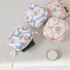 Detailopname van gewatteerde make-uptassen met rozenprint en decoratieve lintritsen