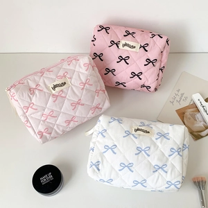 Flat lay of quilted cotton cosmetic bags with bow prints and soft padded texture
