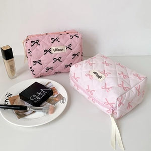 Quilted bow makeup bag with ribbon zipper pull for travel and storage organization