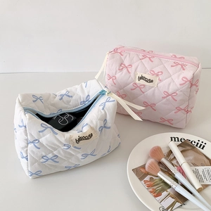 Detail of quilted cosmetic bag showing ribbon bow patterns and spacious interior storage