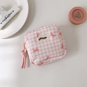 Détail de la trousse de maquillage à carreaux roses avec motif de nœud rouge