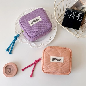 Detailed view of quilted cotton mini pouches in purple and orange with woven zipper pulls
