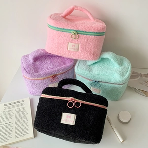 Close-up of colorful plush makeup bags with Lucky Gate labels and metal zippers