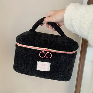 Large black plush makeup bag with pink zipper and bow label for travel organization