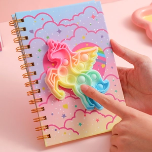Detail of unicorn pop-it silicone cover and gold spiral binding on decompression notebook