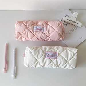 Close-up of pink and white quilted pencil cases with cute fabric labels on desk