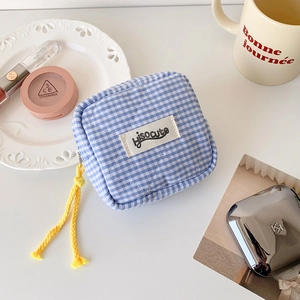Detailed close-up of a blue checkered mini pouch with yellow rope zipper on a white tray