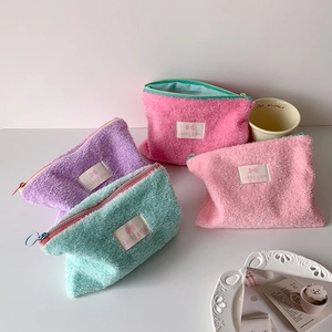Set of four colorful plush makeup bags in pastel pink, purple, and green with zipper
