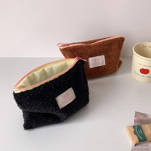 Detail of plush cosmetic bags in black and brown with pink zippers and label