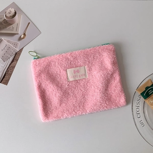 Detailed view of pink plush pouch with lamb wool texture and mint green zipper accents